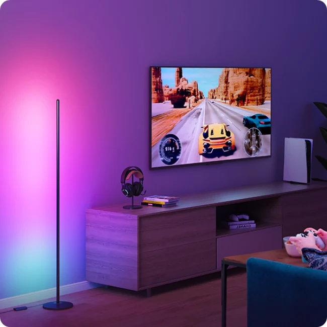 Govee floor lamp placed beside a TV screen displaying a game, with dynamic colors illuminating the room.