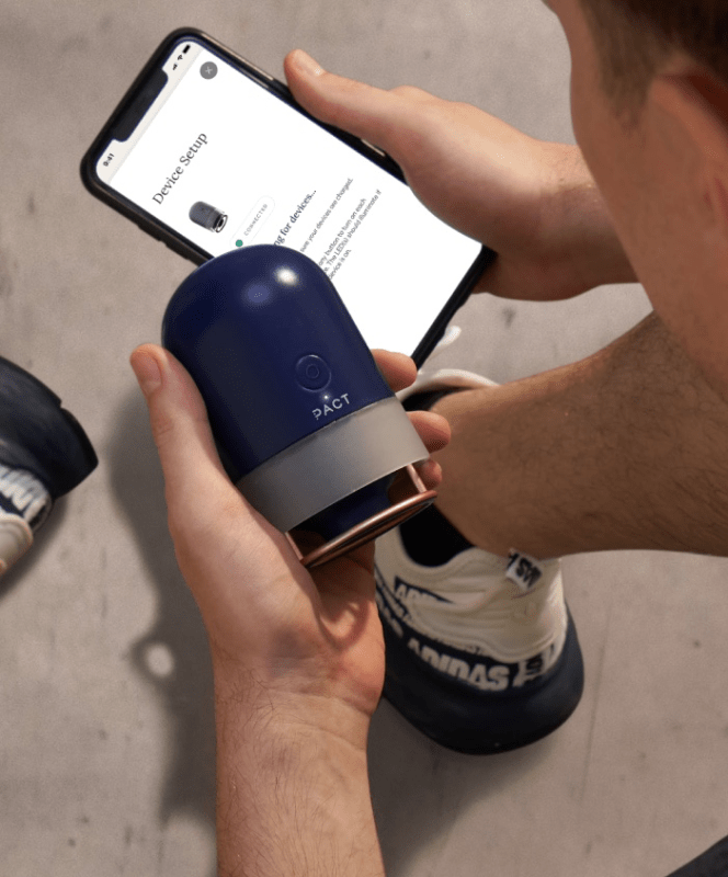 Person holding the Pact Muscle Scanner in one hand and the app on the other hand