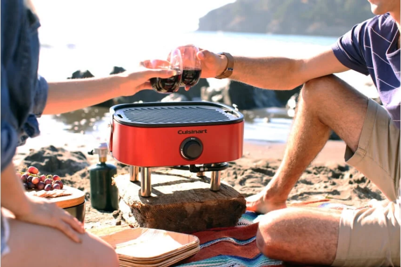 Portable gas grill cooking food by the shore