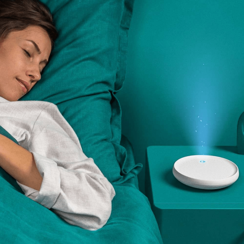 Dodow sleep aid device next to a woman sleeping in bed