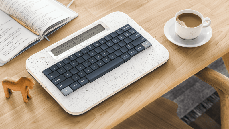 Freewrite Alpha placed on a table with a cup of coffee.