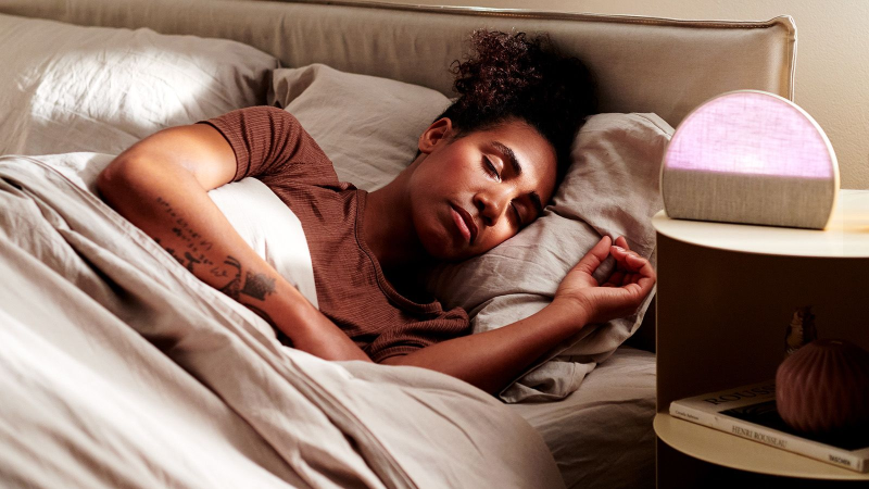 Woman peacefully sleeping with Hatch Restore 2 on the bedside table