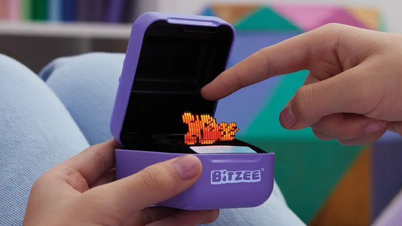 Child playing with Bitzee virtual pet on handheld device