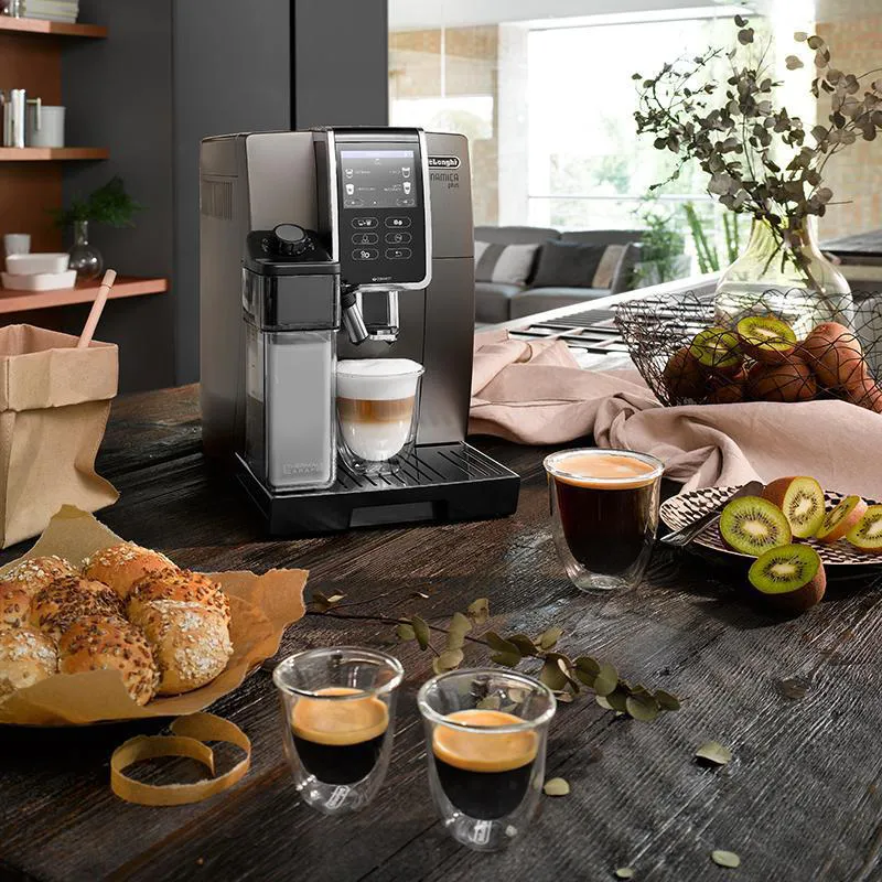 De'Longhi Dinamica Plus coffee machine on a kitchen table with espresso cups.