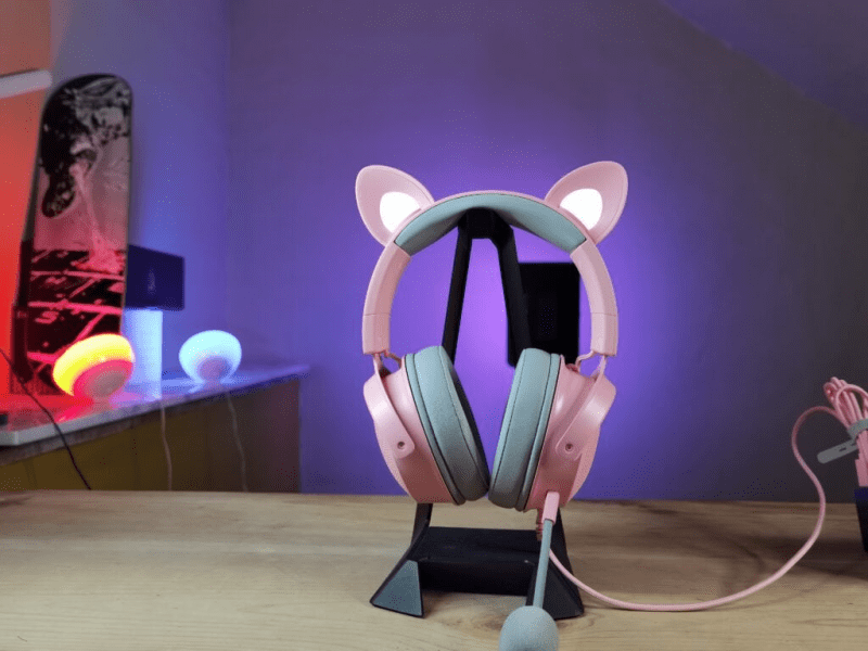 Razer Kraken Kitty V2 headset resting on a table, showcasing its sleek design and pink color.