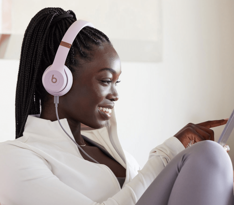 A consumer enjoying music while wearing pink Beats Solo 4 headphones.