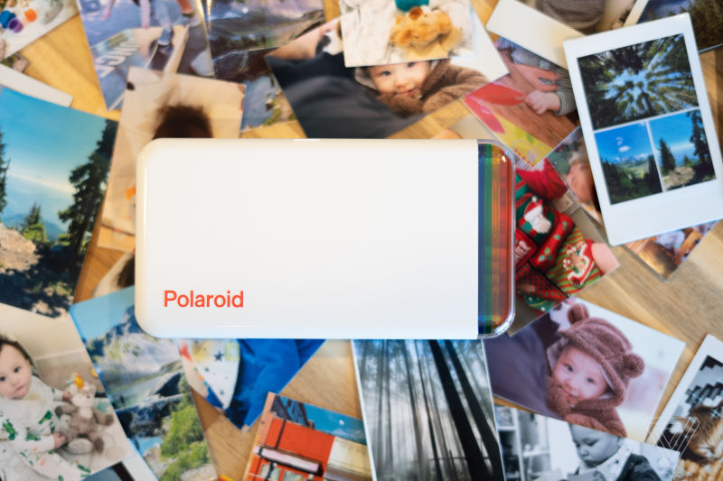 Polaroid Hi-Print device placed on a pile of printed photos