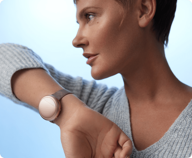 A woman relaxing on a couch, wearing the Embr Wave 2 bracelet and enjoying its cooling function
