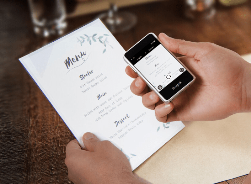 Fluentalk T1 Mini displaying photo translation on its screen while scanning a foreign menu.