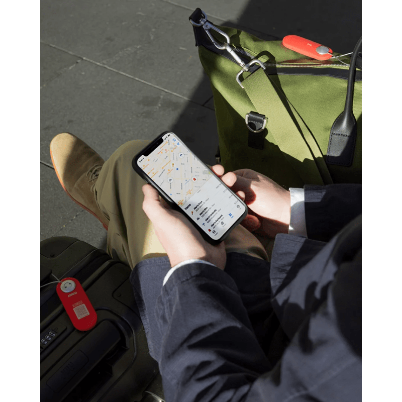 Knog Scout tracker inside a backpack while a traveler checks its location on the Knog app.