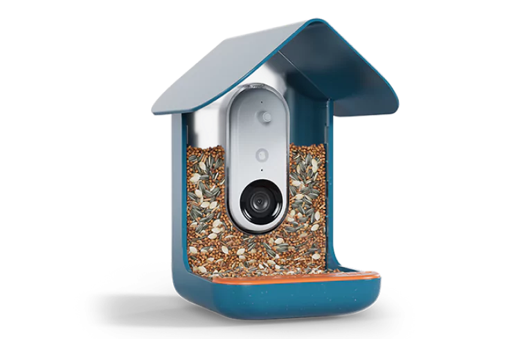 A close-up shot of the Bird Buddy PRO smart bird feeder, focusing on the high-definition camera lens, microphone, and the textured perch for the birds.