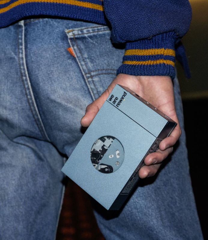 A close-up shot of the We Are Rewind cassette player's top buttons and aluminum body, highlighting the textured metal finish and mechanical "Play/Stop" buttons.