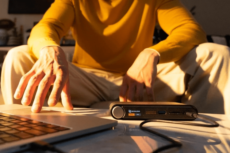 A close-up of the StationPC PocketCloud's front interface, showing the small OLED screen displaying "Backup Complete" and the textured metallic control knob.