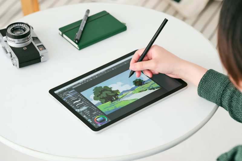 An artist sitting at a small cafe table, sketching comfortably on the MovinkPad Pro 14 without any wires connected.