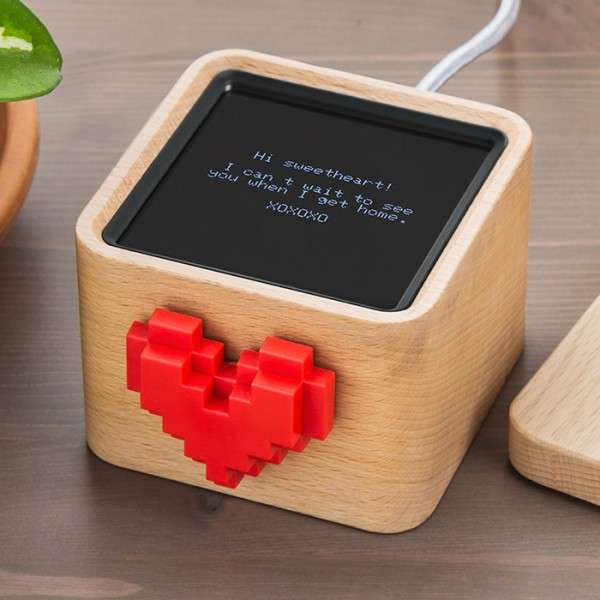 A close-up product shot of the Lovebox, showcasing its natural beechwood construction, rounded corners, and the prominent, chunky red heart on the front face.