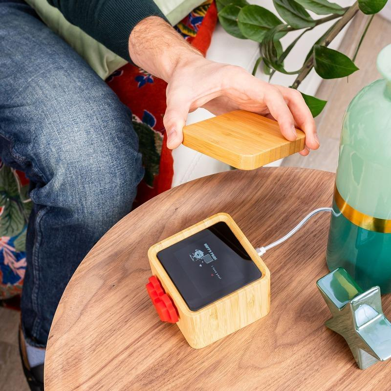 A Lovebox sitting on a cozy bedside table next to a lamp, with the red heart on the front blurred in motion, indicating it is spinning to signal a new message.