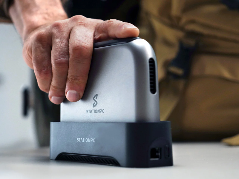 The PocketCloud unit slotted vertically into its sleek docking station on a clean wooden desk, connected via an ethernet cable.